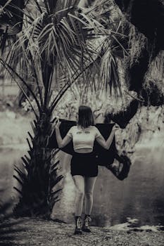 Artistic black and white portrait of a woman outdoors by a riverbank.