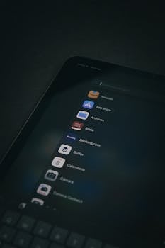 Dark themed close-up of a tablet screen displaying various applications in a vertical shot.